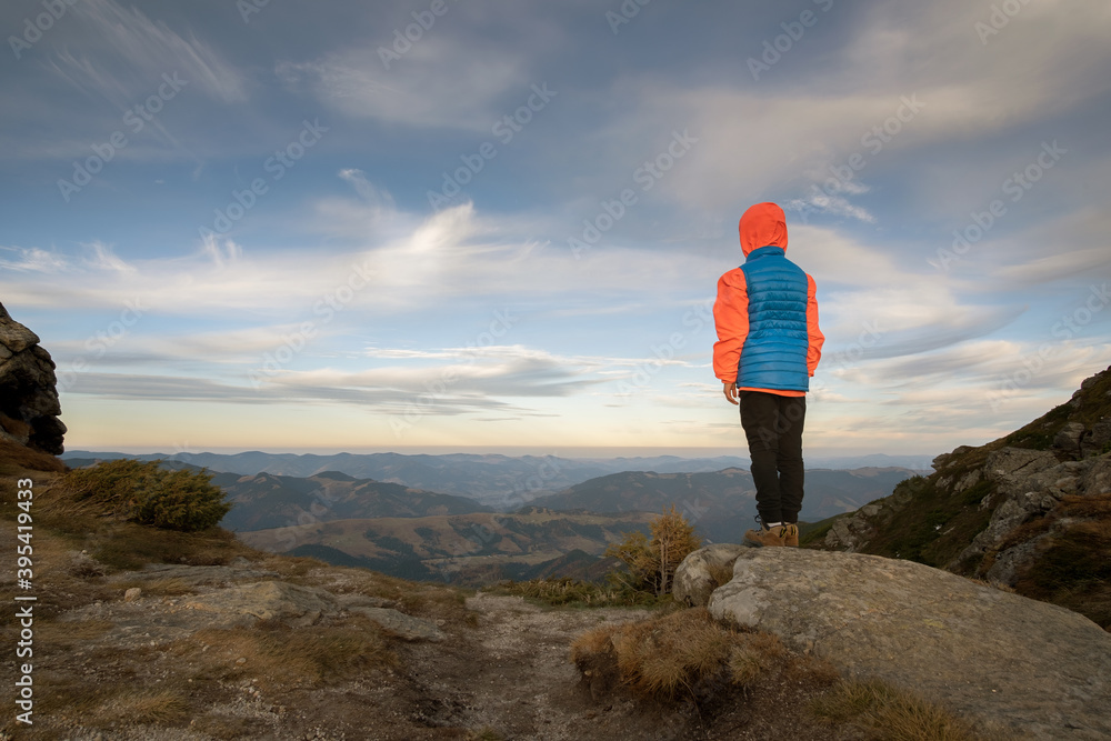 Obraz premium Young child boy hiker standing in mountains enjoying view of amazing mountain landscape.