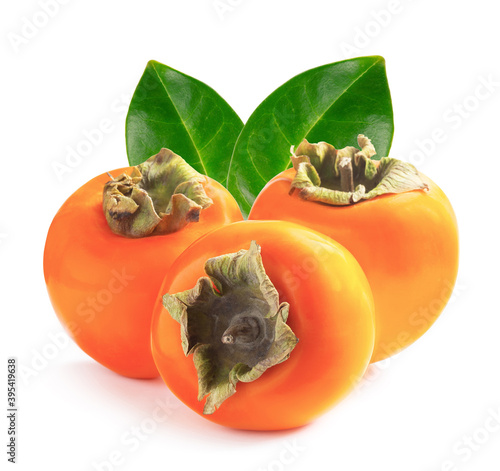 Three ripe persimmons with green leaves
