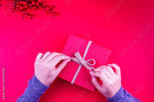 girl opening red christmas gift box in red new year concept (ID: 395420210)