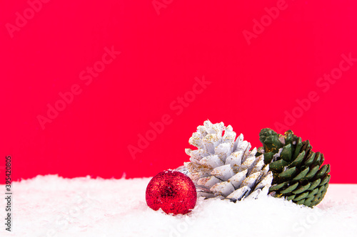 colorful pine cones on red background and snowy backdrop for new year celebration (ID: 395420805)