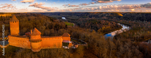Aaerial view to the Turaida castle and river Gauja at sunset in Sigulda, Latvia. Golden autumn with orange forest and river by the castle. photo