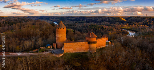 Aaerial view to the Turaida castle and river Gauja at sunset in Sigulda, Latvia. Golden autumn with orange forest and river by the castle. photo