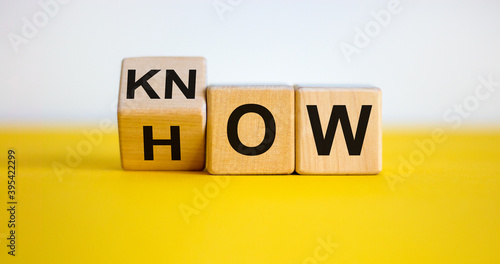Know how and business concept. Turned cube and changed the word 'how' to 'know'. Beautiful yellow table, white background. Copy space.