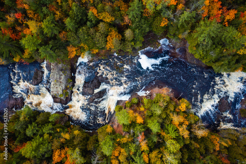 Beautiful look down travel photograph of the upper Potato River Falls waterfall cascades and whitewater rapids cutting through the deciduous and evergreen forest wilderness in Wisconsin.