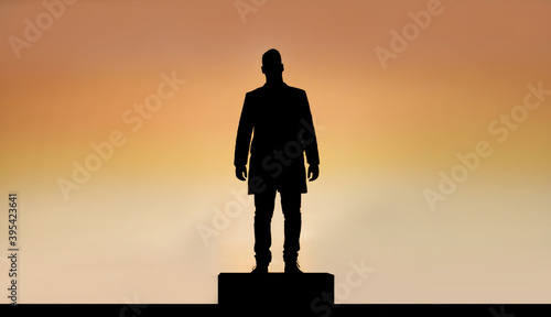 silhouette of man on a podium, warm sky background