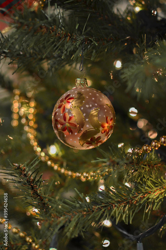 Christmas tree hanging ball ornament close-up with bokeh decorating a Christmas tree with sparkling golden bead string decorations.