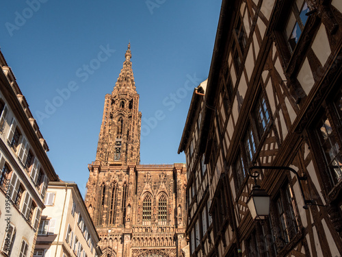 View of the Strasbourg cathedral and its tower from the streets of the old town. Photographed in low angle. Photographed during the summer. Strasbourg is located in Alsace, France.