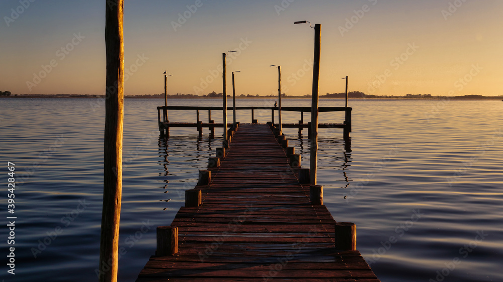  Sunset at Lobos lake, Buenos Aires. Taken from the shore looking to an old large wooden pier and the lake                                            
