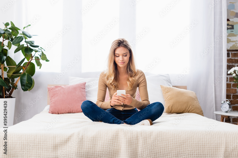woman with crossed legs using smartphone on bed at home woman with crossed legs using smartphone on bed at home
