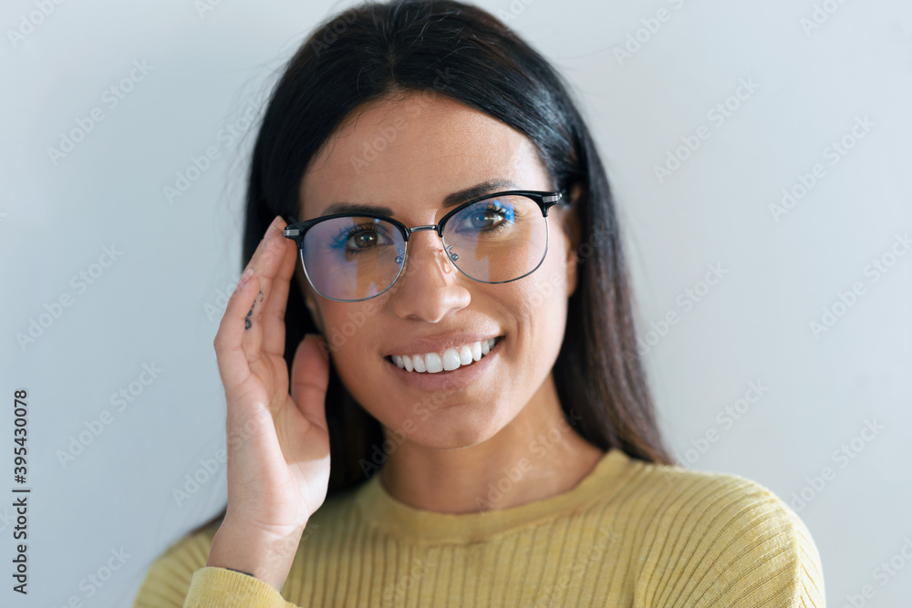 Smiling young woman smiling while looking at camera in the kitchen at home.
