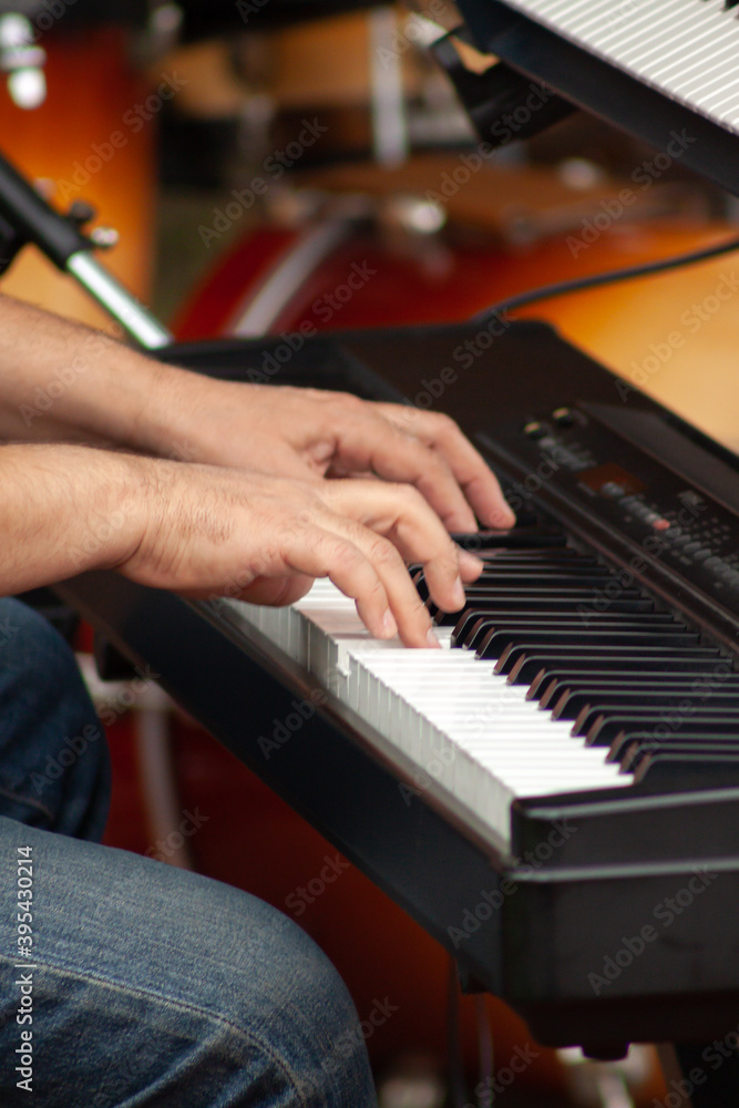Fototapeta premium Hands of a musician or pianist playing a piano keyboard during a musical performance in a square.