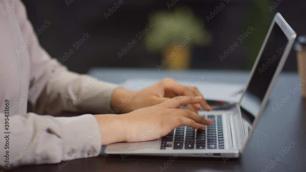 Midsection close up of unrecognizable female hands in selective focus typing on laptop keyboard at office desk Midsection close up of unrecognizable female hands in selective focus typing on laptop keyboard at office desk