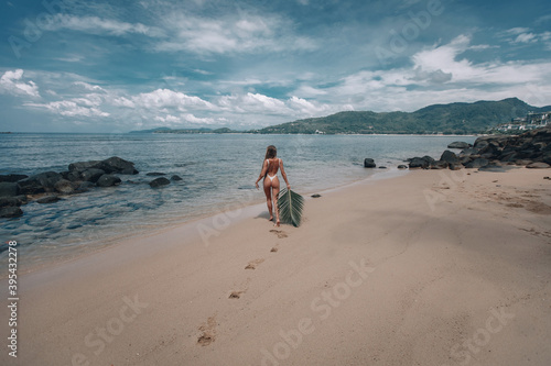 young sexy nude woman holding leaf of palm tree sunbathing on tropical beach. slim body  tanned skin  vacation in Thailand  natural beauty  sunny  summer style. back view