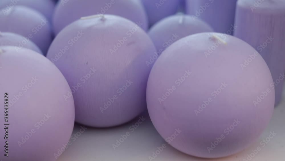 Lilac candles of various round and cylindrical shapes on the shelves look very tactilely attractive. Close-up. The hand takes one of the candle, a selection of a special product. Lilac candles of various round and cylindrical shapes on the shelves look very tactilely attractive. Close-up. The hand takes one of the candle, a selection of a special product.