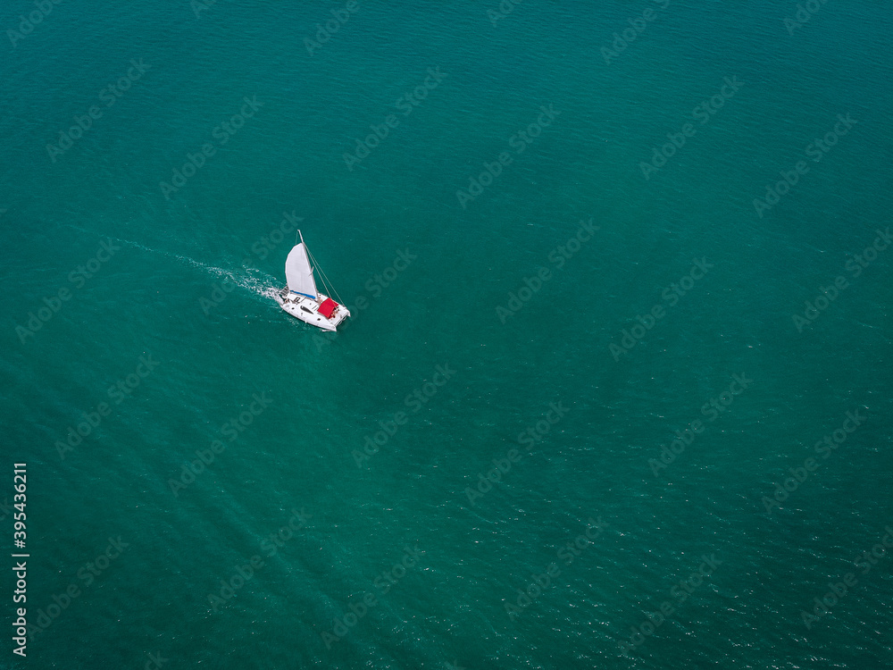 Sailing ship yachts with white sails and  red awning from the sun for passengers at open sea. Aerial - drone view to sailboat in windy condition
