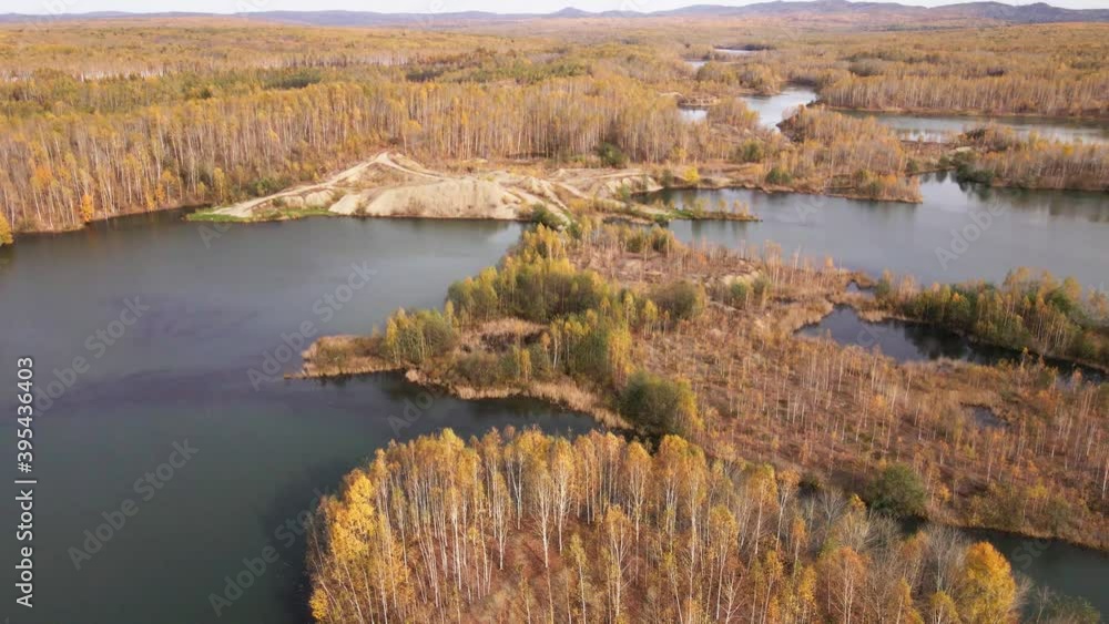 The camera flies over a picturesque poisonous lake surrounded by an autumn forest. Tailings dump left after gold mining The camera flies over a picturesque poisonous lake surrounded by an autumn forest. Tailings dump left after gold mining