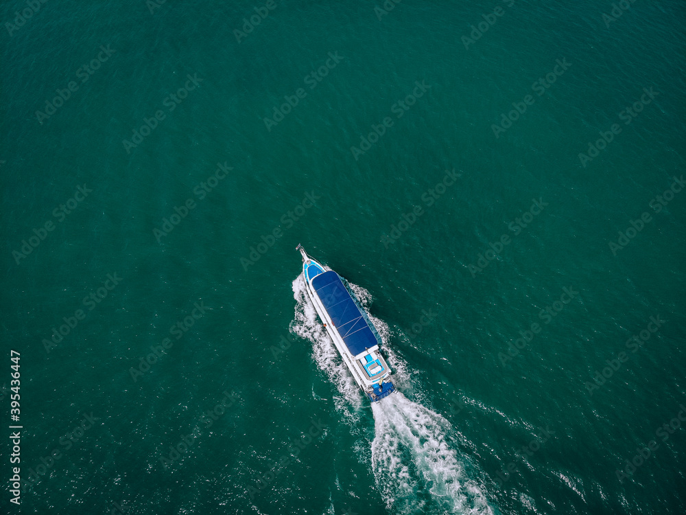 speed Boat/ cruise yacht with blue roof at sea leaving a wake, aerial view