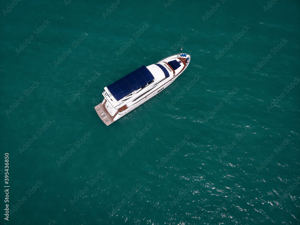 Aerial photo of an isolated luxury white yacht with blue roof design in the sea Aerial photo of an isolated luxury white yacht with blue roof design in the sea