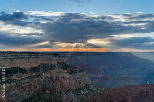 sunset shot of sunbeams extending down from behind clouds at hopi point of the grand canyon national park in arizona