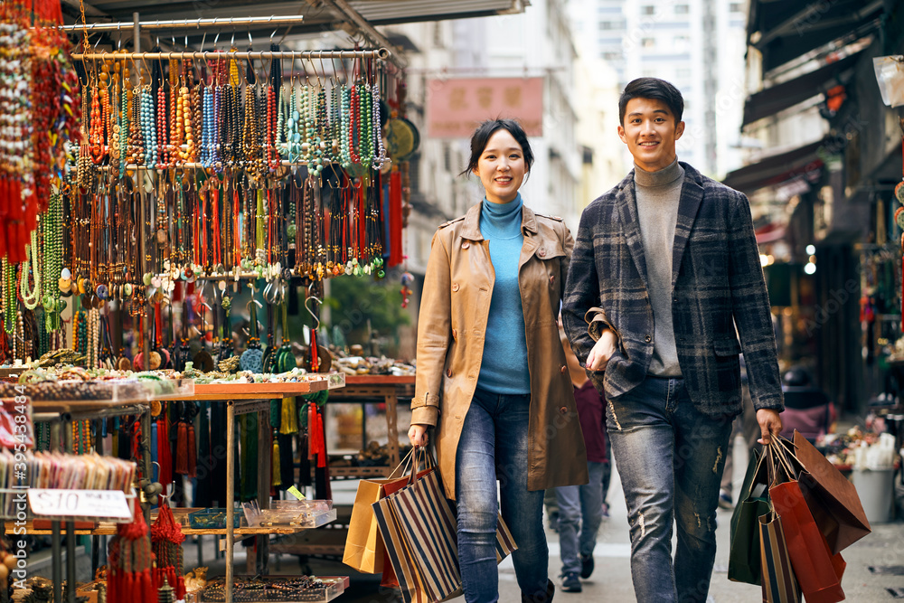 Fototapeta premium young asian couple walking on steps carrying shopping bags
