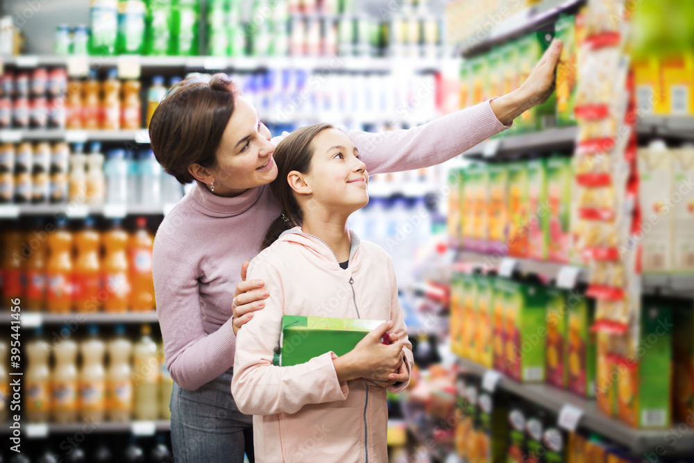 Pretty young woman customer with girl looking for refreshing beverages in supermarket