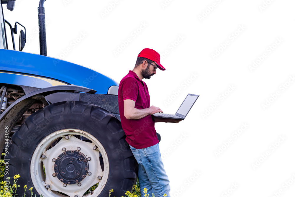 Young farmer is using a laptop in front of blue tractor in farming field. Smart and modern farm concept. With white background Young farmer is using a laptop in front of blue tractor in farming field. Smart and modern farm concept. With white background