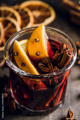 Mulled red wine with oranges and different spices in glass on the rustic background. Christmas food. Winter decorations. Selective focus. Shallow depth of field.