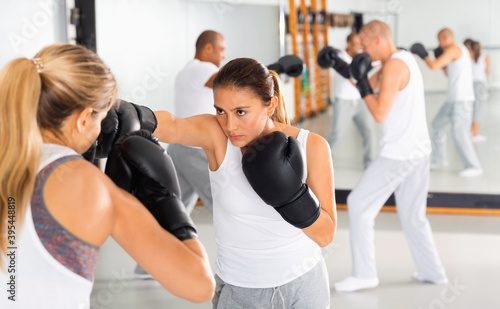 Two efficient serious glad women in boxing gloves have boxing fight in the gym © JackF