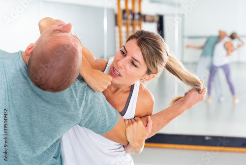 Young woman practicing elbow blow with male partner during self defense course in gym Fototapet