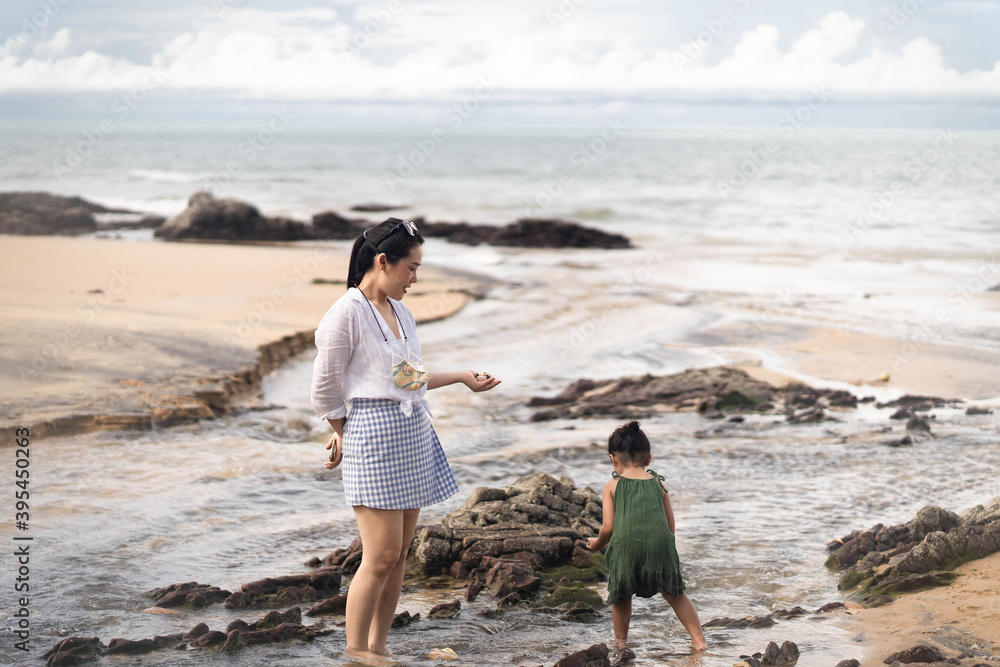 Mother and daughter walking at sea shore a