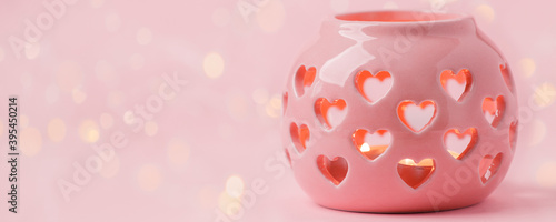 Decorative pink ceramic lanterns with heart cutouts lit by glowing candles onpink background, copy space, Saint Valentine, Mother day, Woman day concept, banner, flyer, greeting card, invitation photo