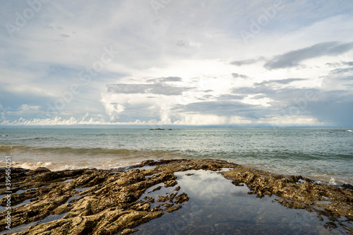 Rocks sea shore against cloudy sky.