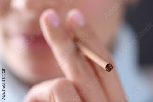 Woman holding cigarette in hand near her mouth closeup. Harm of smoking concept