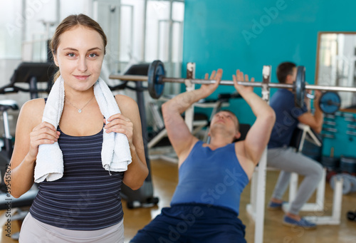 Portrait of sporty girl foreground and practicing men on background in sport club