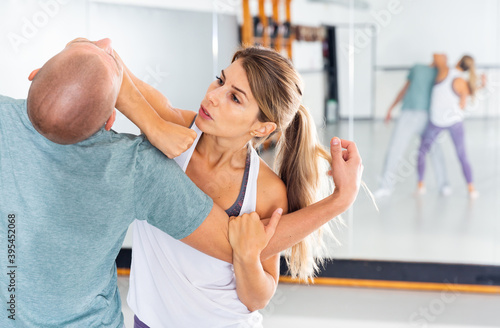 Fotografi Young woman practicing elbow blow with male partner during self defense course in gym