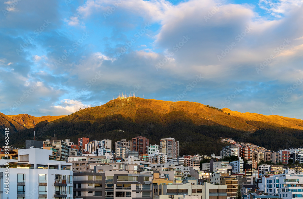 Cityscape and aerial view with skyscrapers of the modern Quito city at sunrise with Pichincha volcano, capital of Ecuador in the Andes mountains.