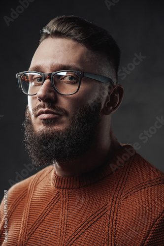 Bearded hipster with stylish hairstyle weared with glasses posing in dark background.