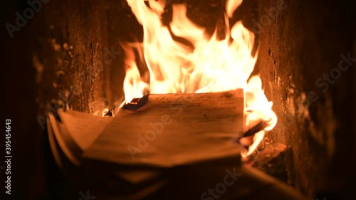 Blazing hot fire flame warming old fireplace burning wood logs, paper letters, documents, books manuscripts in dark dusk coal ash cinder