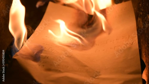 Blazing hot fire flame warming old fireplace burning wood logs, paper letters, documents, books manuscripts in dark dusk coal ash cinder