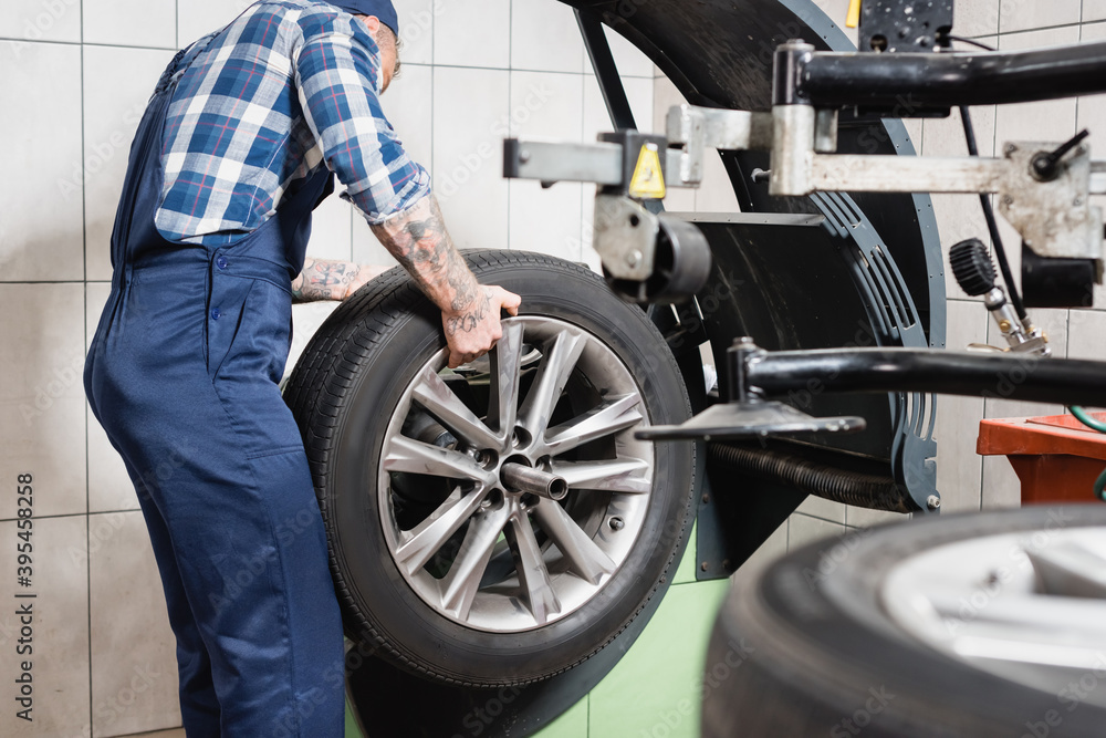 Fototapeta premium cropped of technician examining wheel on balance control machine in garage on blurred foreground