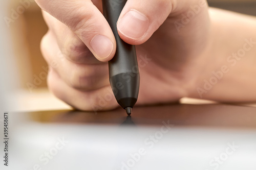 Girl draws on a graphics tablet with pen. Close-up  selective focus