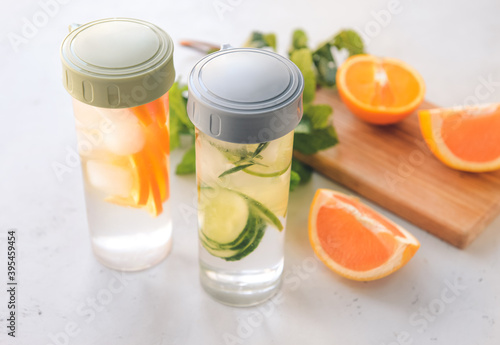 Bottle of mint infused water with orange on light table