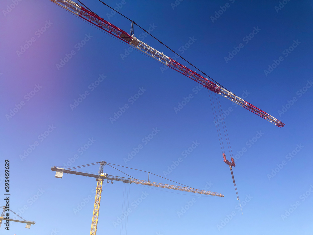Booms of tower cranes against blue sky. Lifting machinery at construction site Booms of tower cranes against blue sky. Lifting machinery at construction site