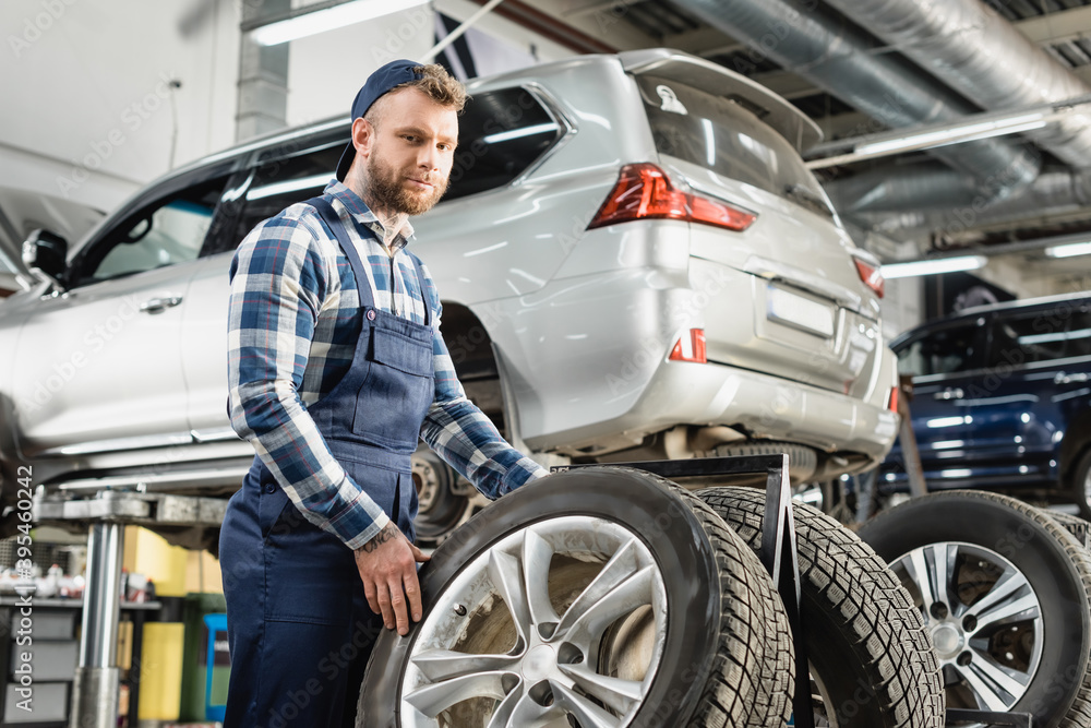 mechanic looking at camera near wheel and auto raised on car lift mechanic looking at camera near wheel and auto raised on car lift