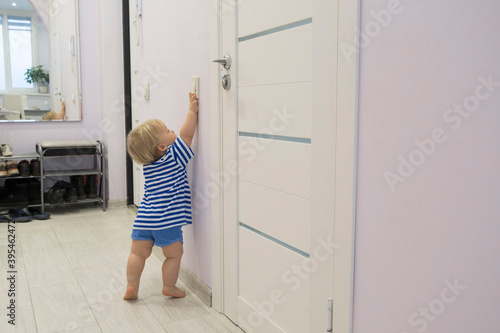 little boy reaches for the light switch, baby stands on tiptoe and tries to turn on the light in the room.