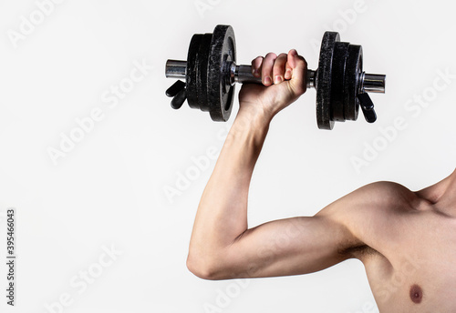 Man hand holding dumbbell in hand. Skinny guy hold dumbbells up in hands. A thin man in sports with dumbbells. Weak hand man lift a weight, dumbbells. Nerd maleraising a dumbbell