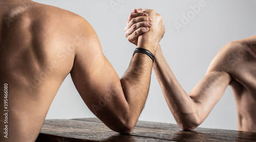 Two man's hands clasped arm wrestling, strong and weak, unequal match. Arm wrestling. Heavily muscled man arm wrestling a puny weak man. Arms wrestling thin hand and a big strong arm in studio photo