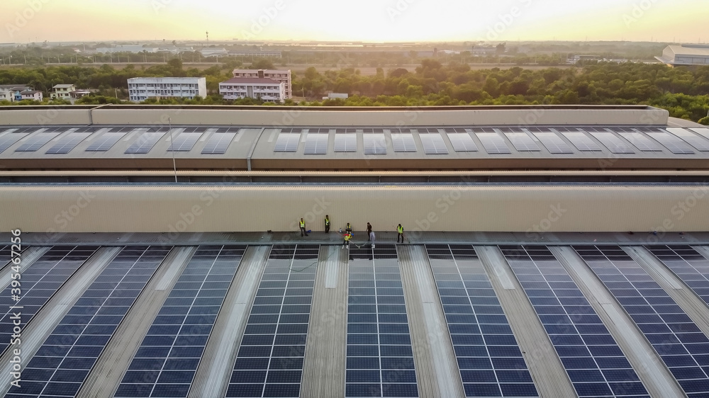 Solar panels installed on a roof of a large industrial building or a warehouse. Industrial buildings in the background. Horizontal photo. Solar panels installed on a roof of a large industrial building or a warehouse. Industrial buildings in the background. Horizontal photo.