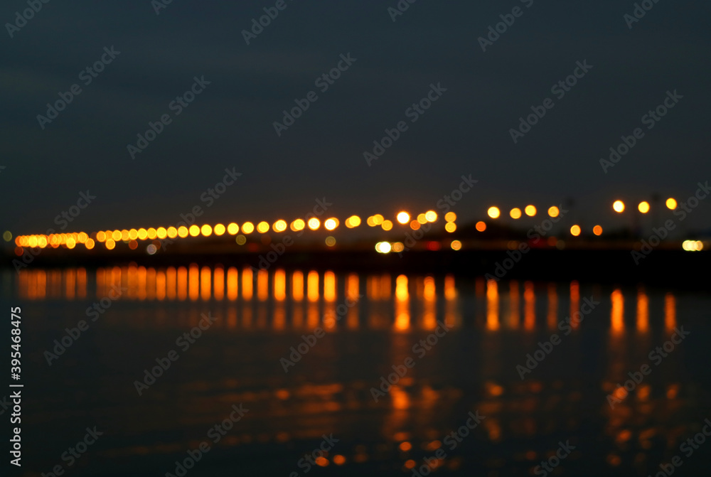 Abstract Blurred Sea Bridge at Night with the Reflections of Lighting on the Sea