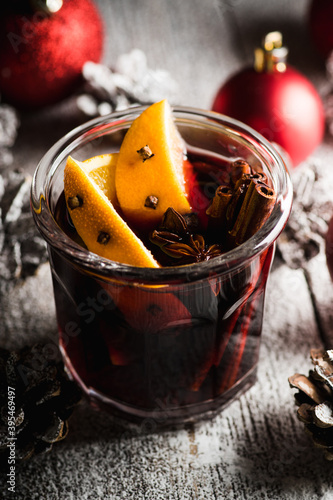 Mulled red wine with oranges and different spices in glass on the rustic background. Christmas food. Winter decorations. Selective focus. Shallow depth of field. 